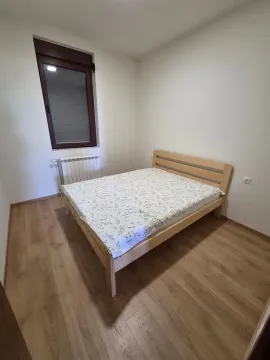 Manja spavaća soba sa bračnim krevetom, drvenim podom i prozorom. - image 9