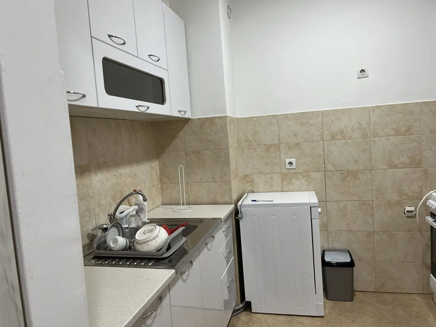 A simple kitchen with white cabinets and a washing machine.