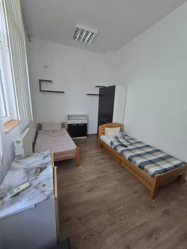 Spavaća soba sa dva drvena kreveta, ormanom i stolom. - image 3