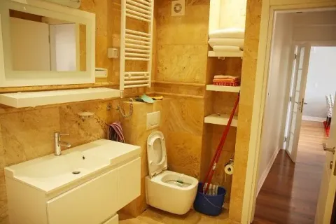 Kupatilo obloženo žutim mermerom sa umivaonikom, WC šoljom i policama za peškire. - image 14