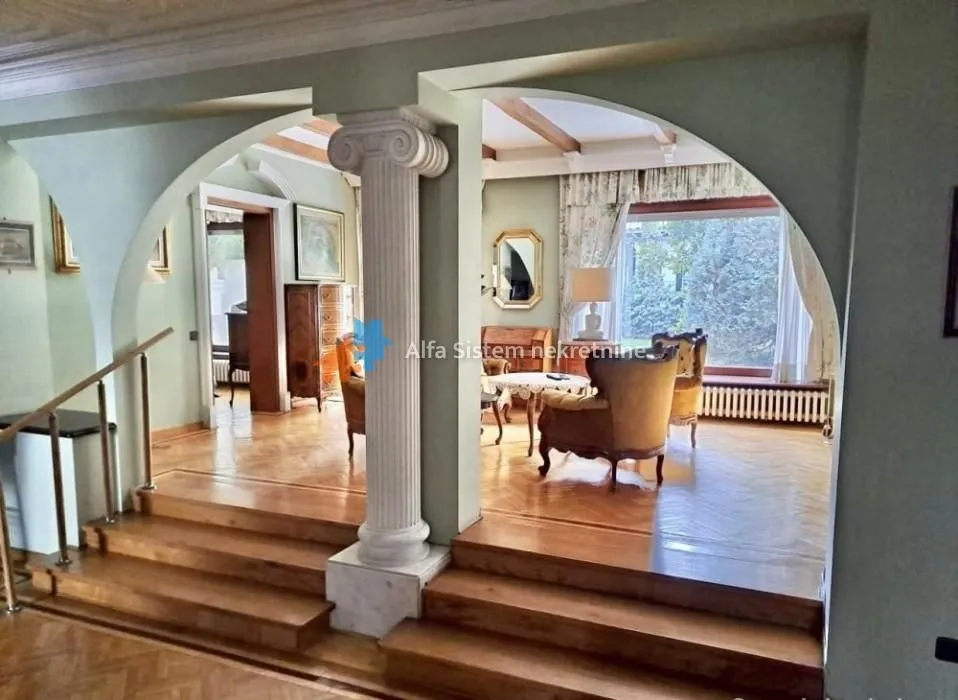 Spacious living room with a column and stairs.