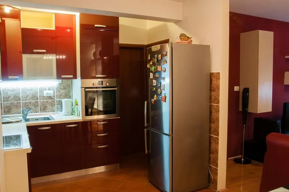 Kitchen with dark red cabinets and a stainless steel refrigerator.