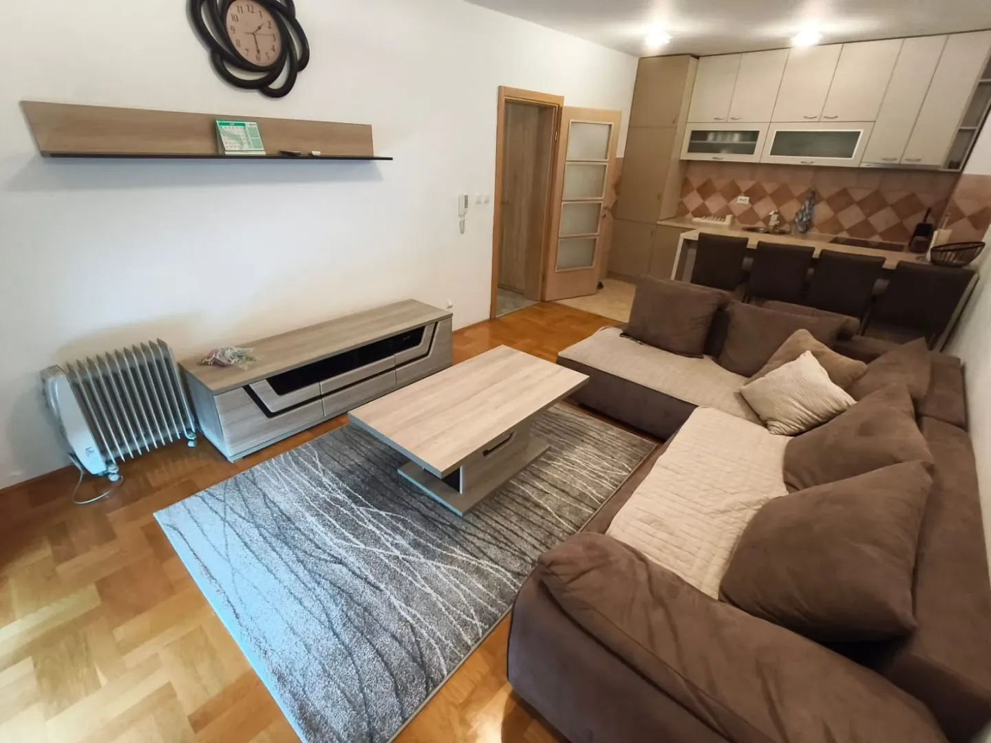 Living room with a sofa, coffee table, and a view of the kitchen with dining area.