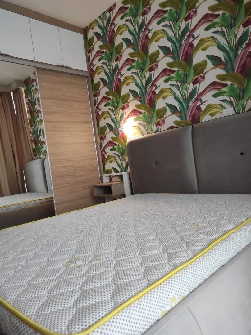 Furnished bedroom with a double bed, wardrobe, and patterned wallpaper.