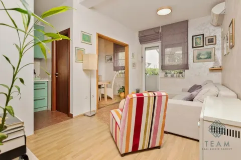 Living room with a sofa, colorful armchair, and a passage to the dining area. - image 5