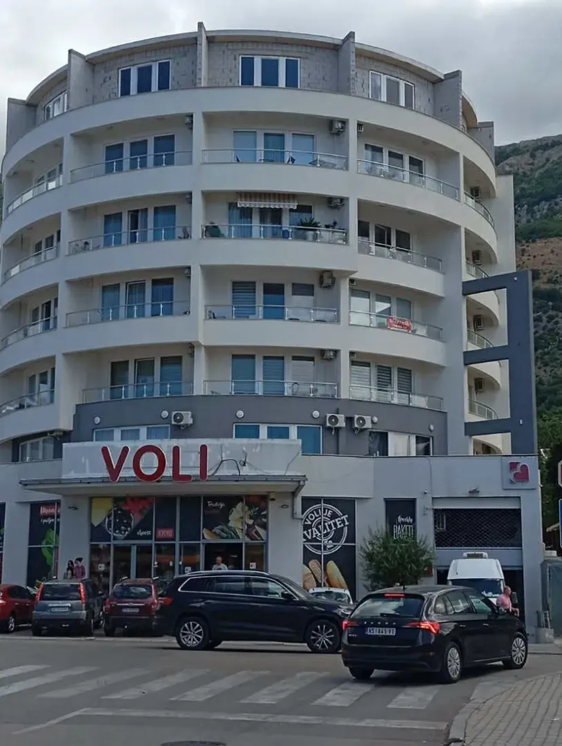 Exterior view of a multi-story residential and commercial building with a supermarket on the ground floor.