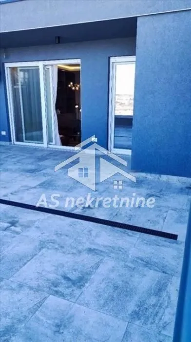 Spacious terrace with tiled flooring and entrance to the apartment.