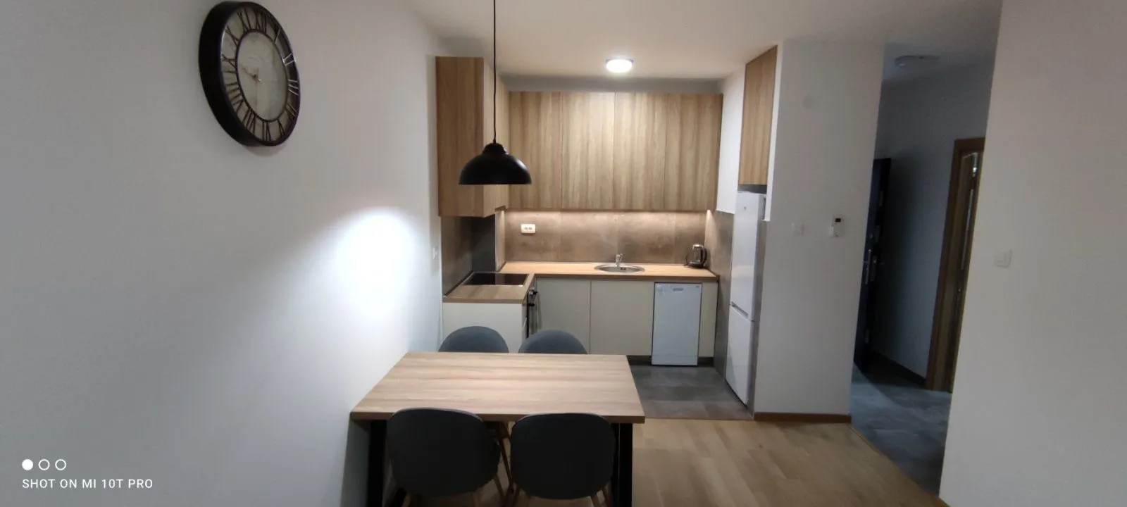 Kuhinja sa drvenim elementima i trpezarijskim stolom sa četiri stolice.