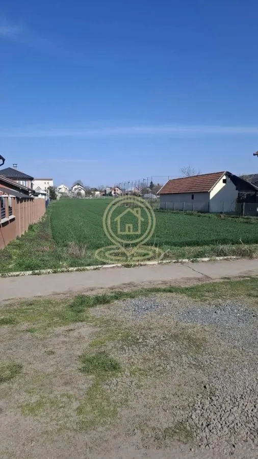 Pogled na plac sa travnatom površinom i okolnim objektima.