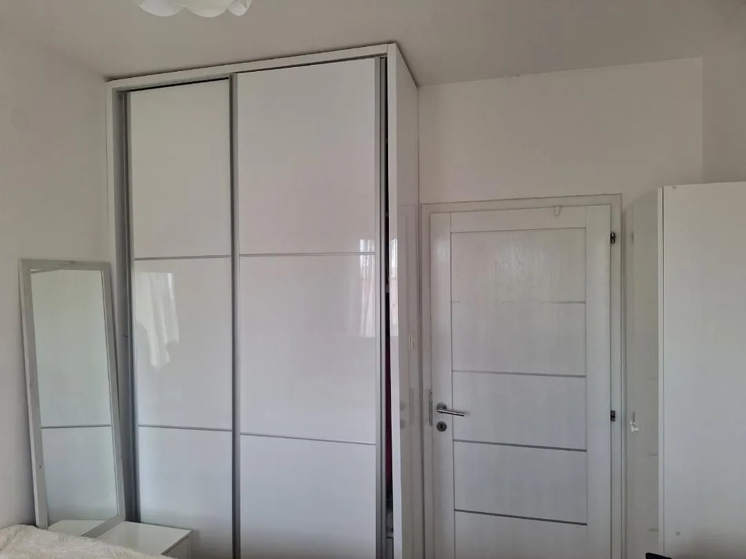 A bedroom with a large white wardrobe and a door.