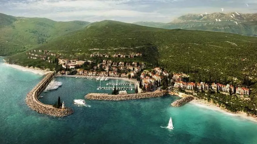 Pogled iz vazduha na obalu sa marinom i naseljem u zelenilu.