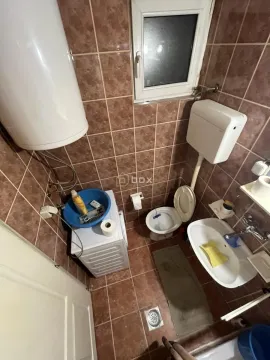 Manje kupatilo obloženo braon pločicama sa toaletom, umivaonikom i veš mašinom. - image 8