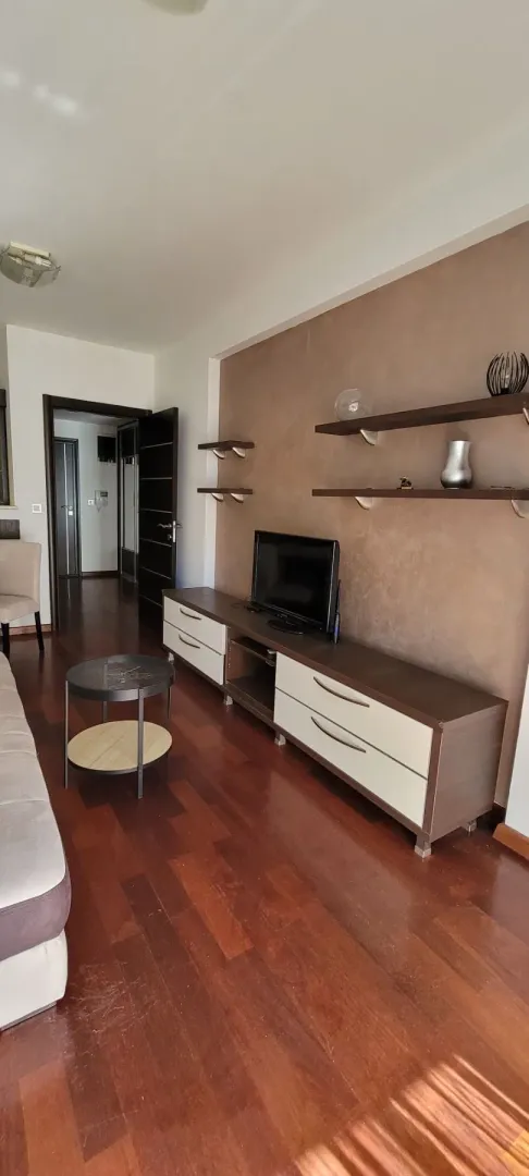 Dnevna soba sa garniturom, televizorom i drvenom komodom.