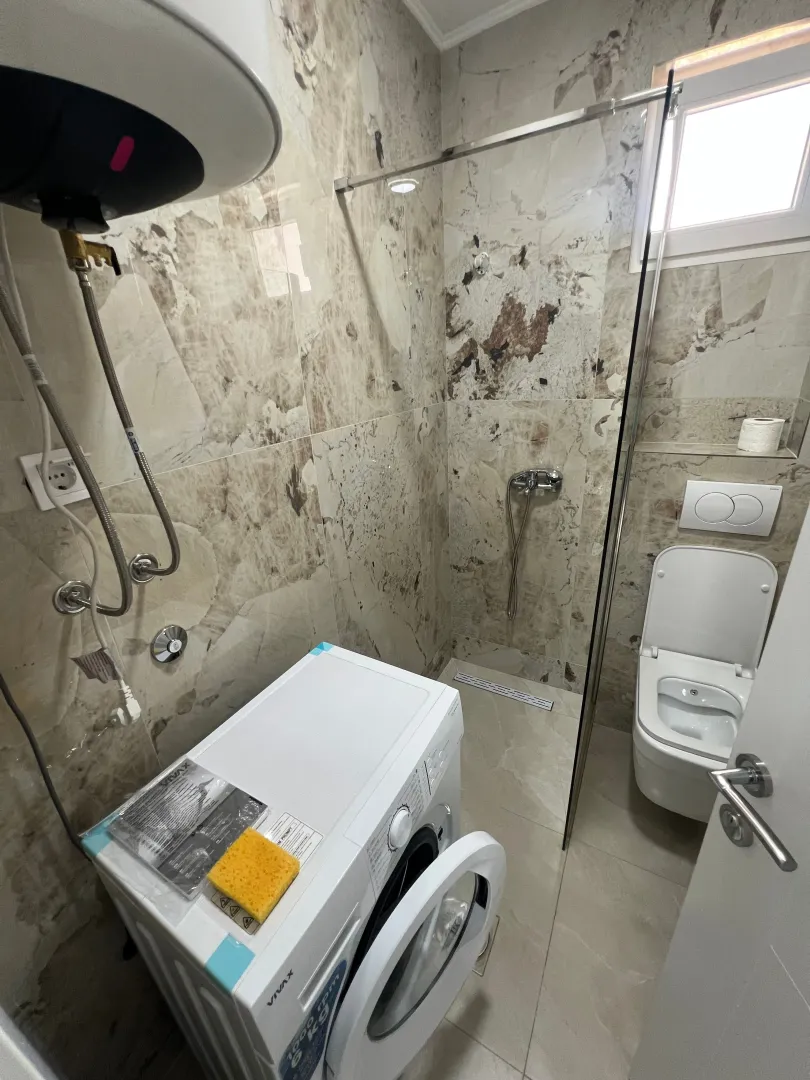 Modern bathroom with a walk-in shower, toilet, and washing machine.