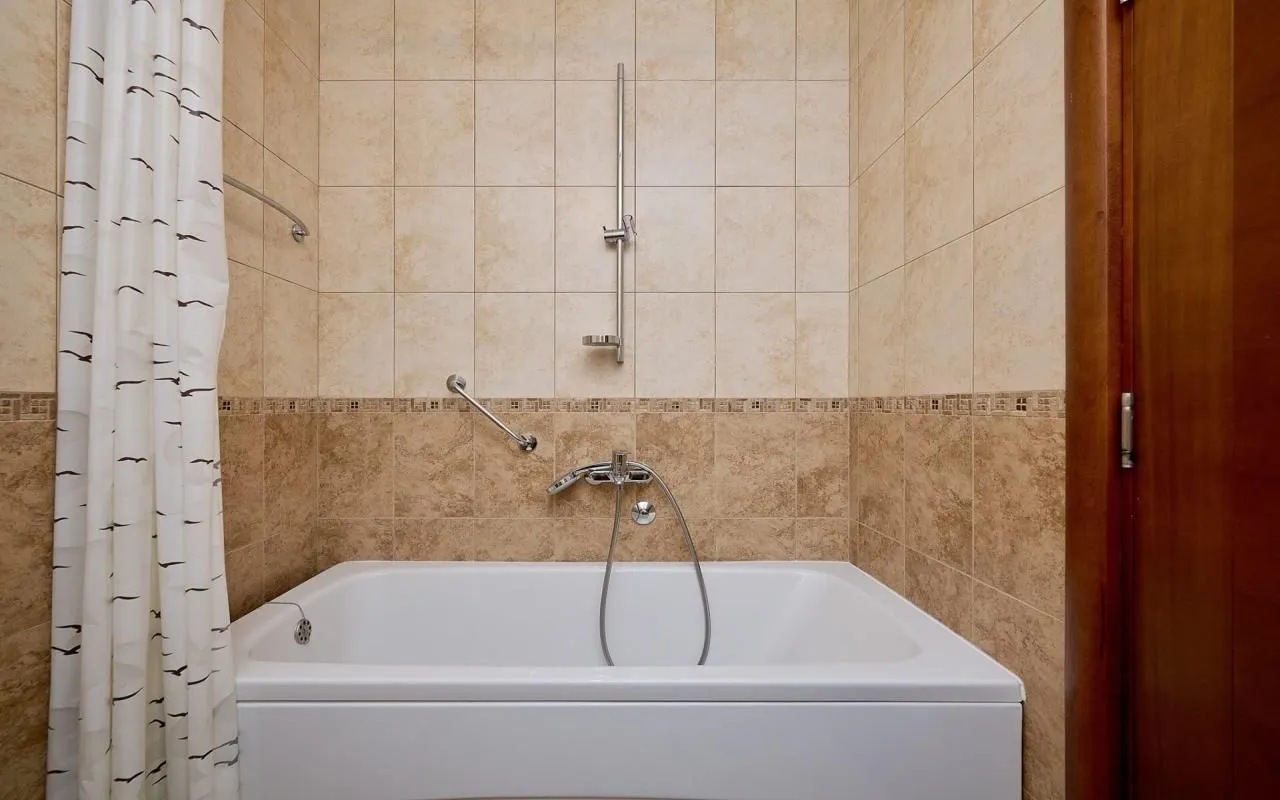 Bathroom with a bathtub and beige tile walls.