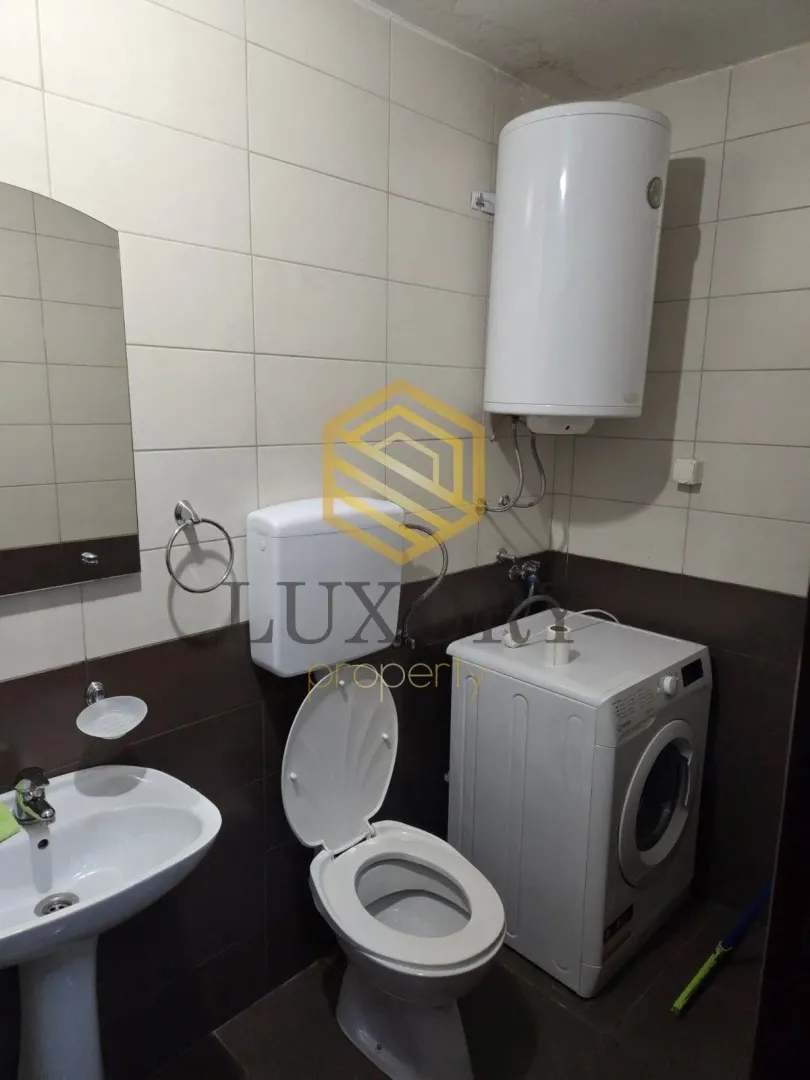 Small bathroom with a sink, toilet, water heater, and washing machine.
