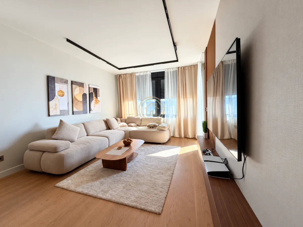 Living room furnished with a sectional sofa, coffee table, and wall-mounted TV.