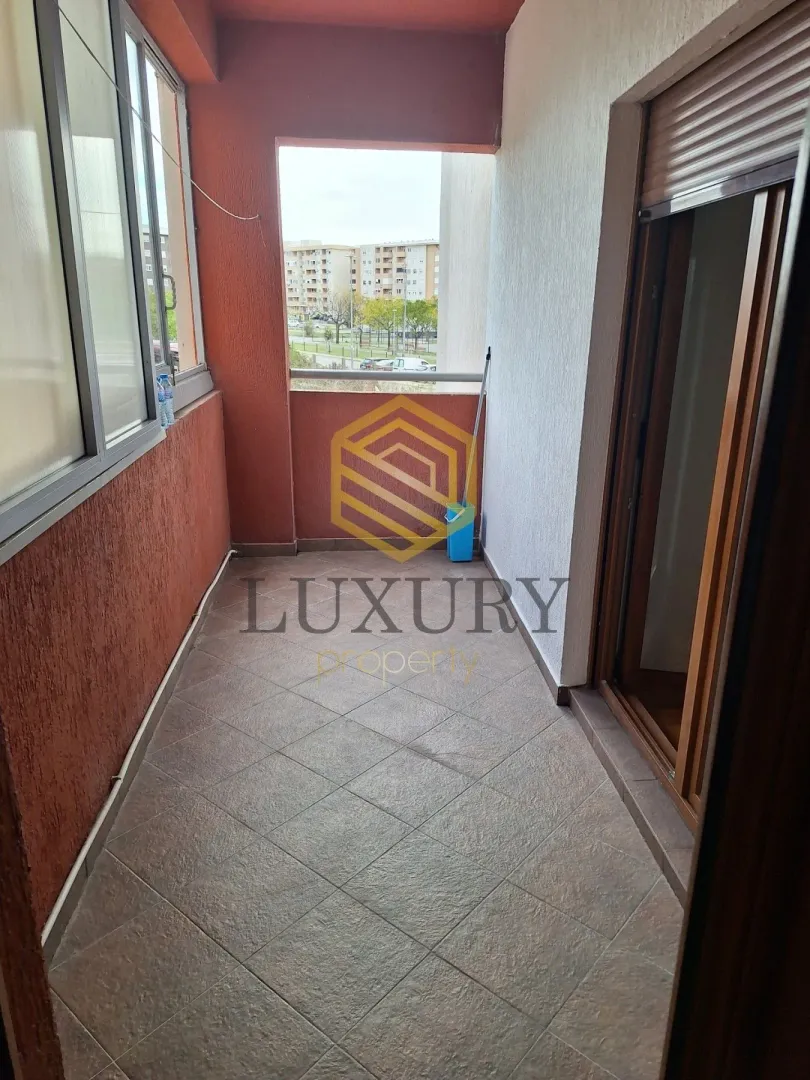 Covered balcony with tiled flooring and a view of surrounding buildings.