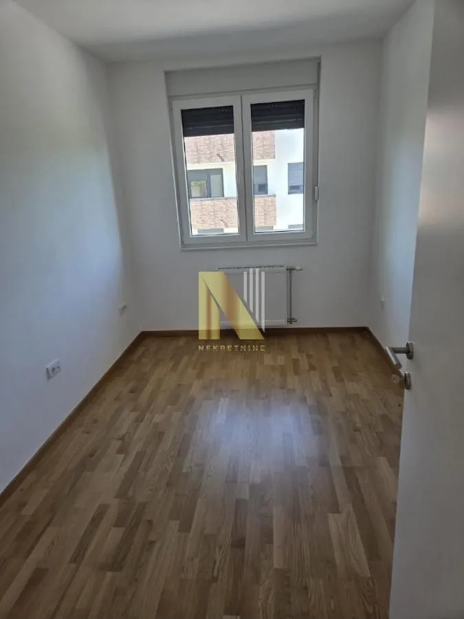 Prazna soba sa parketom i prozorom.