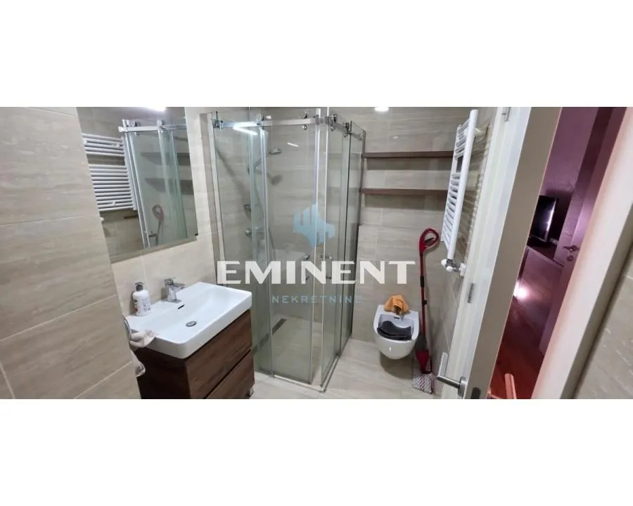 Modernly equipped bathroom with a shower cabin, washbasin, and toilet.