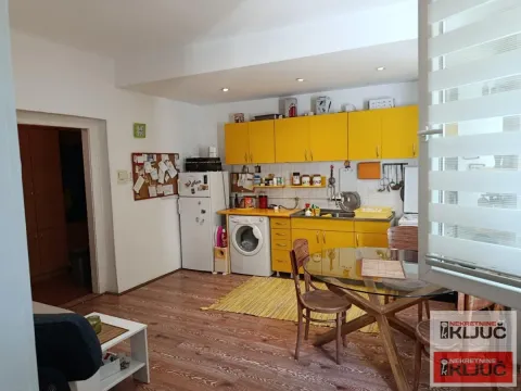 Kuhinja sa žutim elementima i trpezarijskim stolom. - image 3