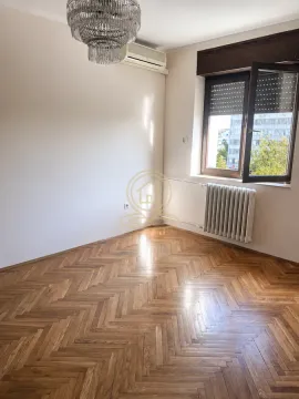 Prazna soba sa parketom, lusterom, klima uređajem i prozorom. - image 3