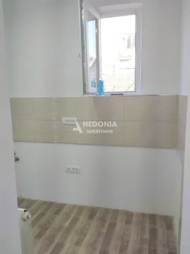 Prazan kuhinjski prostor sa pločicama na zidu i prozorom. - image 4