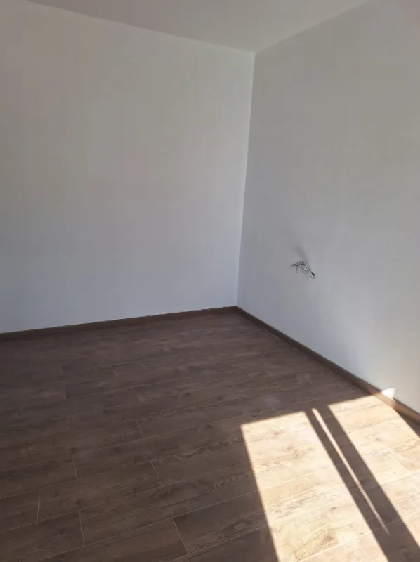 Empty room with white walls and a wooden floor.