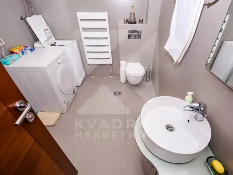Modern bathroom with a washing machine, washbasin, and toilet. - image 4