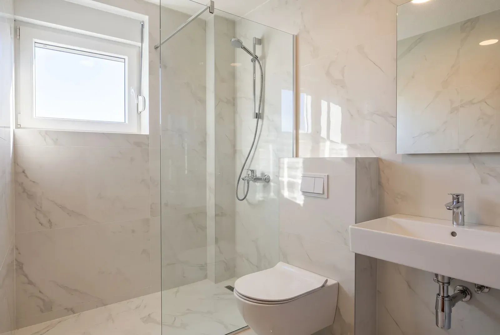 Modern bathroom equipped with a walk-in shower, washbasin, and toilet.