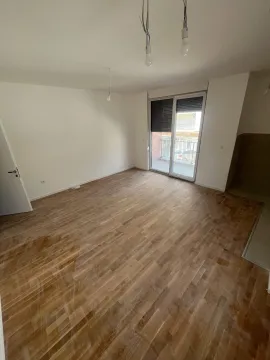 Prazna soba sa drvenim parketom i balkonskim vratima. - image 3