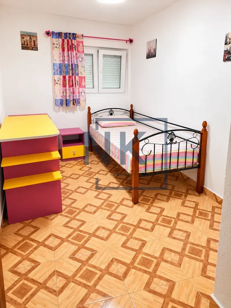 Children's bedroom with a bed, colorful bedding, and a chest of drawers.