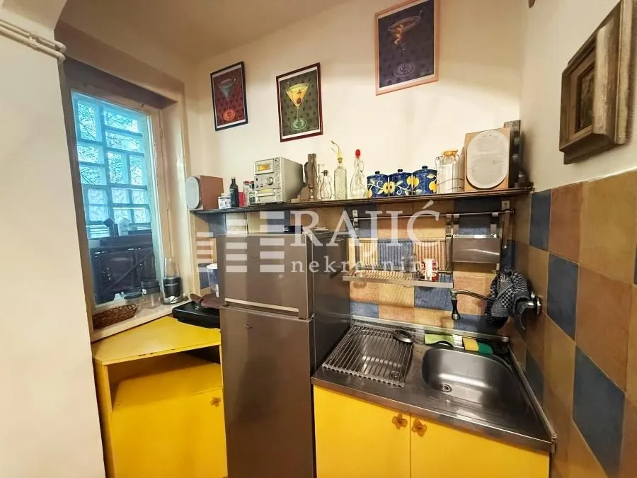 Small kitchen with yellow cabinets and a refrigerator.