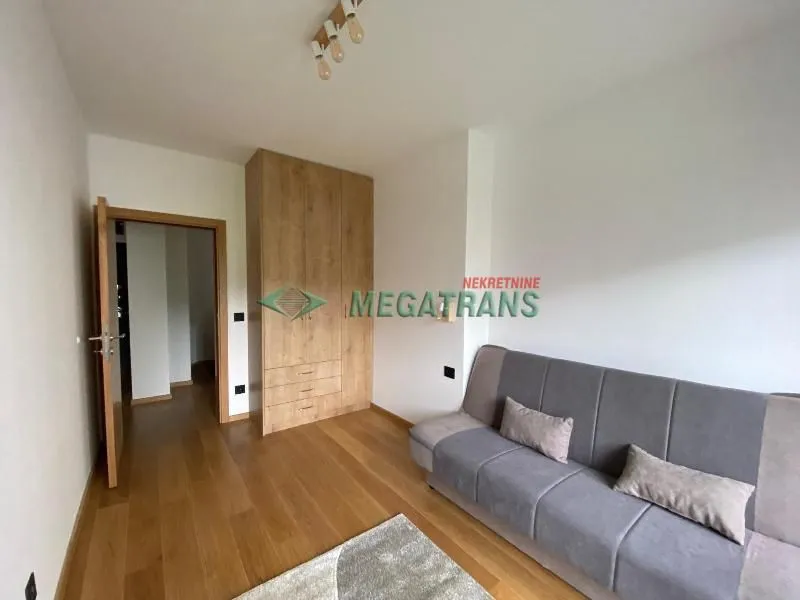 Living room with a sofa, wooden wardrobe, and parquet flooring.