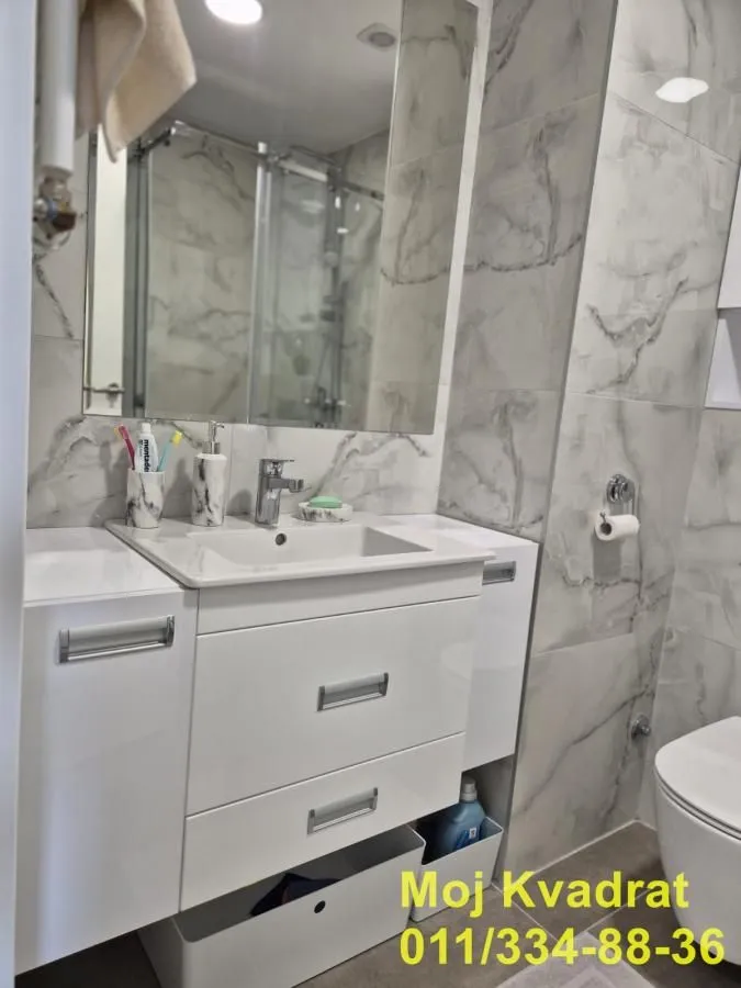 Modern bathroom with a white sink, mirror, and marble-look tiles.