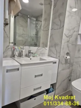 Modern bathroom with a white sink, mirror, and marble-look tiles. - image 9