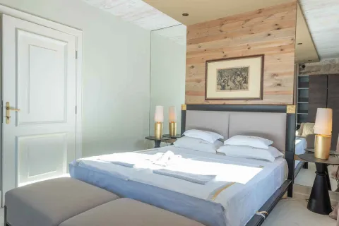 Bedroom with a double bed, wooden wall paneling, and a white door. - image 3
