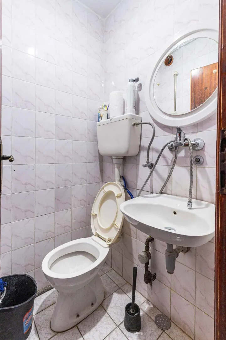 A small bathroom with a toilet, sink, and mirror.
