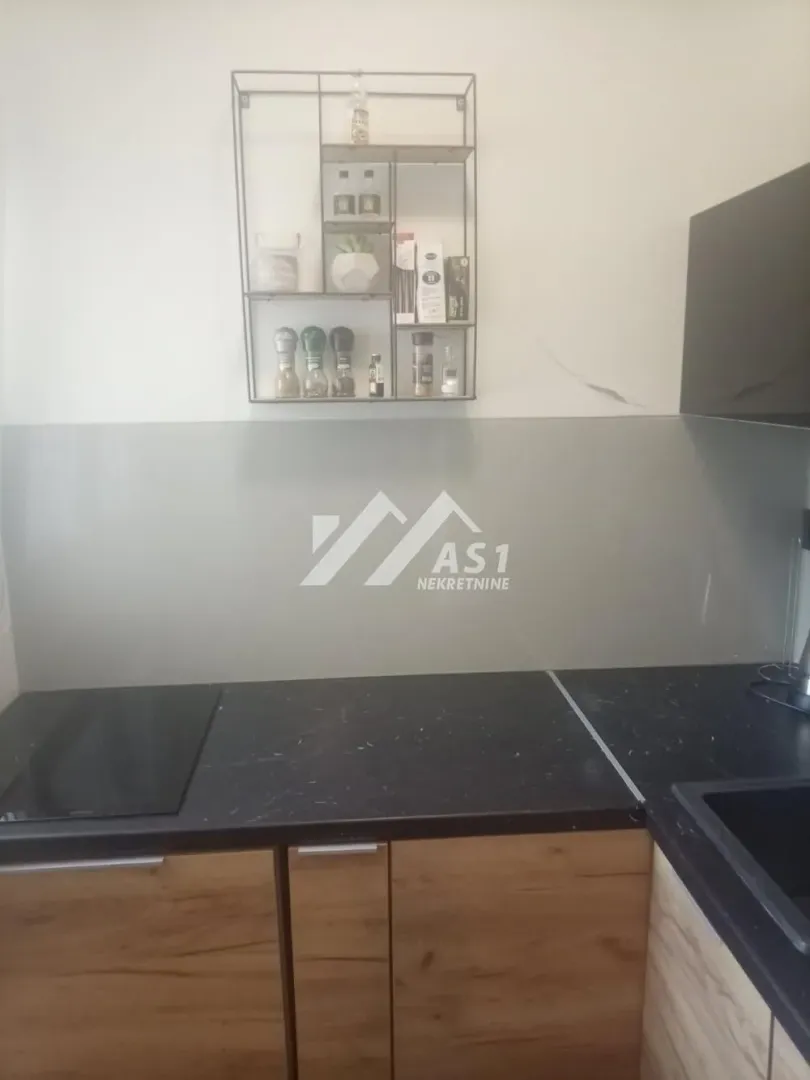 Part of the kitchen with countertop, sink and wall shelf.