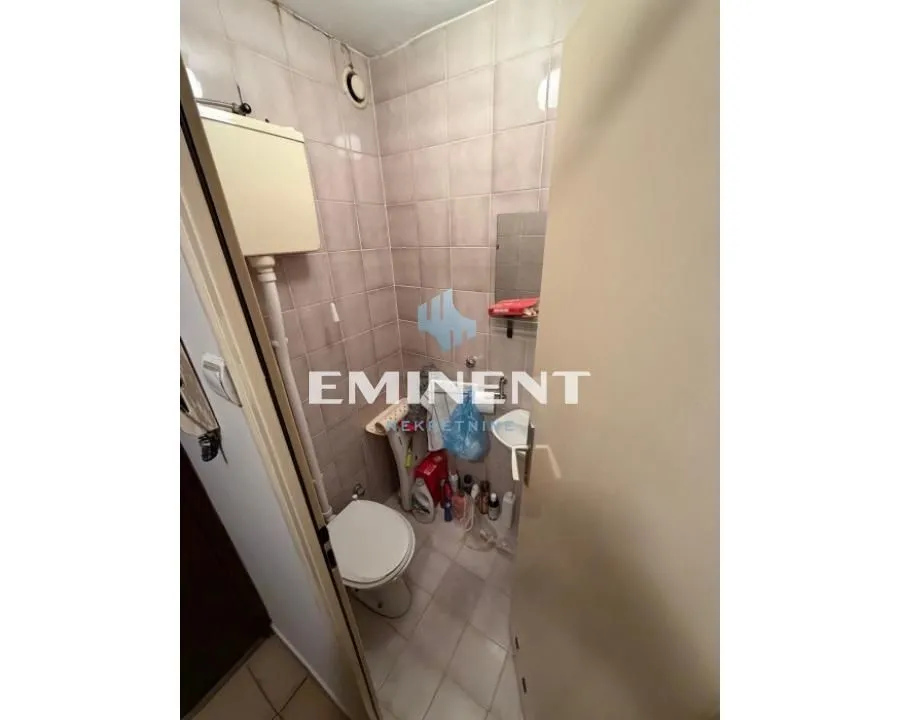 Small tiled bathroom with a toilet and a washbasin.