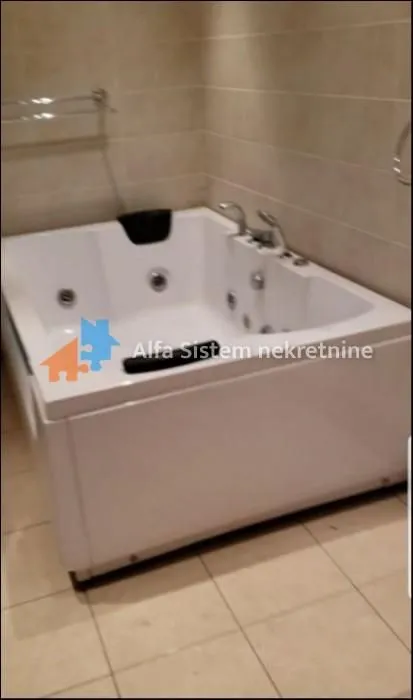 Bathroom with a corner whirlpool bathtub and ceramic tiles.
