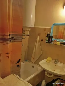 Small bathroom with a bathtub, washbasin, and water heater. - image 16