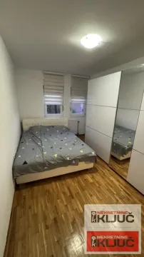 Nameštena spavaća soba sa bračnim krevetom i velikim belim ormarom. - image 5