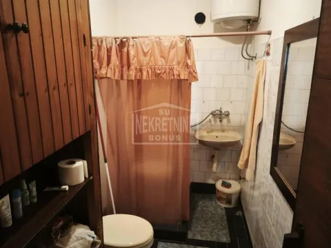 Starije opremljeno kupatilo sa tuš zavesom, umivaonikom i WC šoljom. - image 12