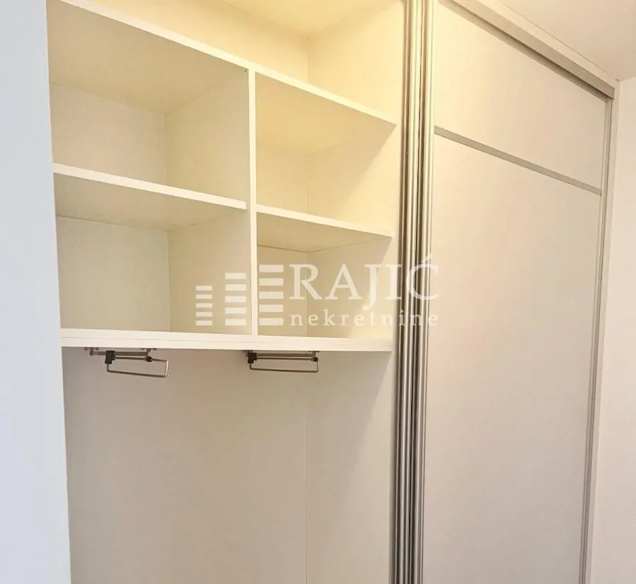 White built-in wardrobe with open shelves and a clothes rail in the room.
