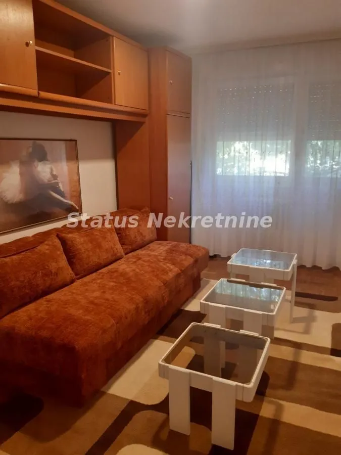 Dnevna soba sa garniturom, drvenim elementima i manjim stočićima.