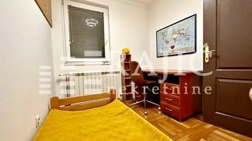 Small bedroom with a bed, desk, and window.