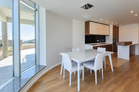 Dining area with a white table and chairs next to a modern kitchen and large windows. - image 5