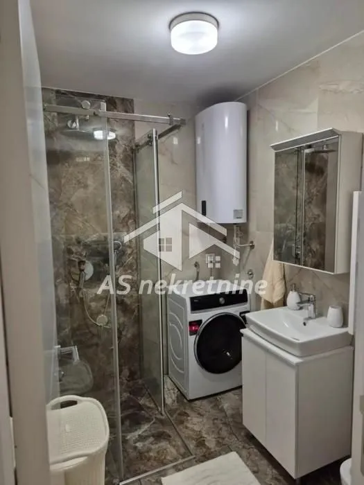 Bathroom equipped with a walk-in shower, washbasin, washing machine, and water heater.
