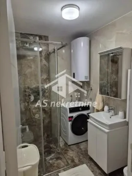 Bathroom equipped with a walk-in shower, washbasin, washing machine, and water heater. - image 22